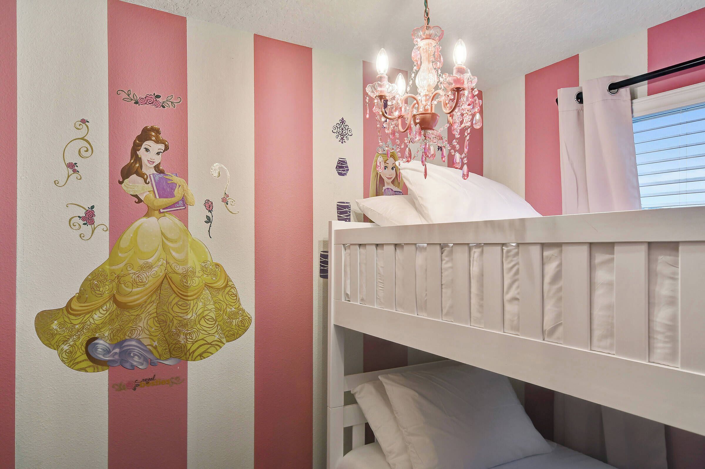 A bedroom with a bunk bed, a decorative wall with a princess mural, and a chandelier.