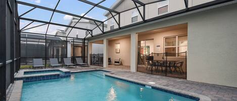 Ein Pool mit Glasveranda, Liegestühlen und Essbereich mit Tischen und Stühlen.