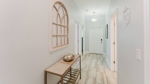 A hallway with a wooden table, a bowl, and a door at the end. - Storey Lake 5BR Family Home w/ Private Pool (Kissimmee)