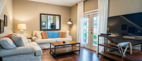A living room with a sofa, coffee table, TV, and a lamp.