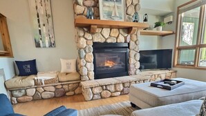 Ein gemütliches Wohnzimmer mit Kamin, bequemen Sitzmöglichkeiten und einem Fernseher.