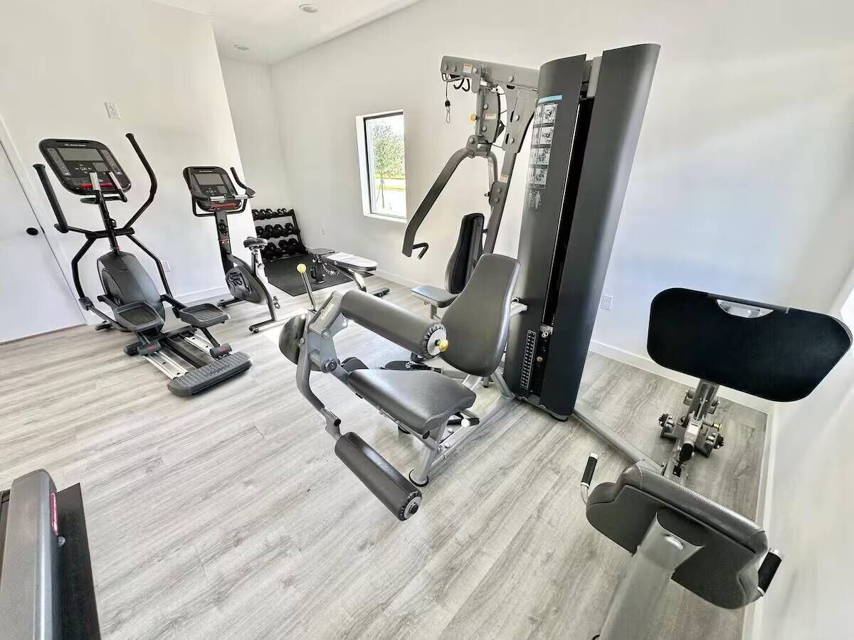 Un gimnasio con cintas de correr, una banca de pesas y una máquina de remo.