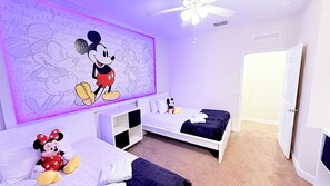 A bedroom with two beds, a Mickey Mouse mural, and a Minnie Mouse plush toy. - Renovated 3BR Home | Mickey Room | Near Disney (Kissimmee)