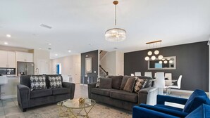 En moderne stue med to sofaer, et sofabord og et spiseområde med en lysekrone.