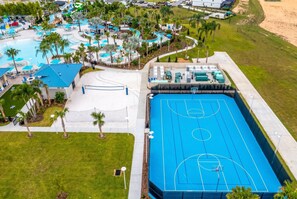 Ett semesterområde med en swimmingpool, en basketplan och ett område med strand.