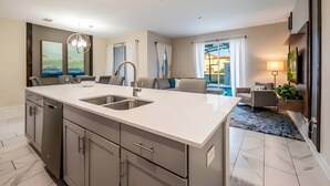 A modern kitchen with a large island, built-in appliances, and a view to the living area. - Luxury 4BR Villa w/ Pool Near Disney Parks (Davenport)
