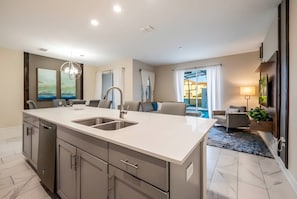 Una cocina moderna con una isla grande, electrodomésticos integrados y vistas al área de estar.