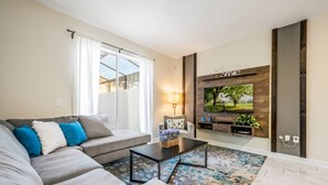 A living room with a sofa, coffee table, TV, and a rug. - Luxury 4BR Villa w/ Pool Near Disney Parks (Davenport)