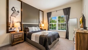 A bedroom with a bed, bedside tables, a TV, and a window with curtains. - Luxury 4BR Villa w/ Pool Near Disney Parks (Davenport)