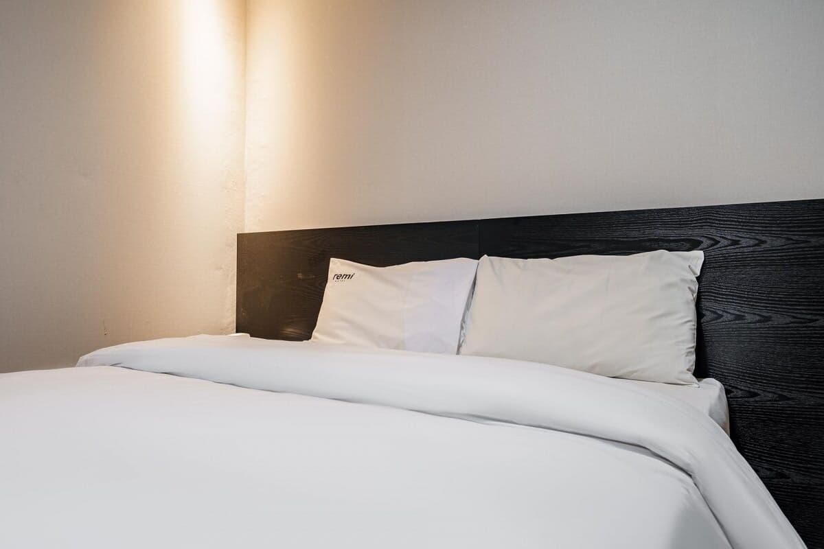 A bed with white bedding and a dark headboard in a hotel room.
