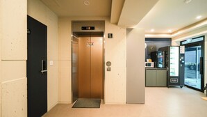 An elevator in a hallway with a digital display, a door with a number, and a vending machine. - Hotel remi (Seoul)