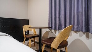 A hotel room with a bed, two wooden chairs, a small table, and a window with curtains. - Hotel remi (Seoul)