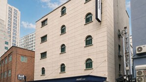 A multi-story hotel with a flat facade, a covered entrance, and a parking garage. - Hotel remi (Seoul)