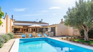A swimming pool with blue water, surrounded by lounge chairs and a covered patio area.