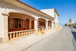 Ein Gebäude mit heller Fassade, mehreren Bögen und einem dahinterliegenden Stein-Turm.