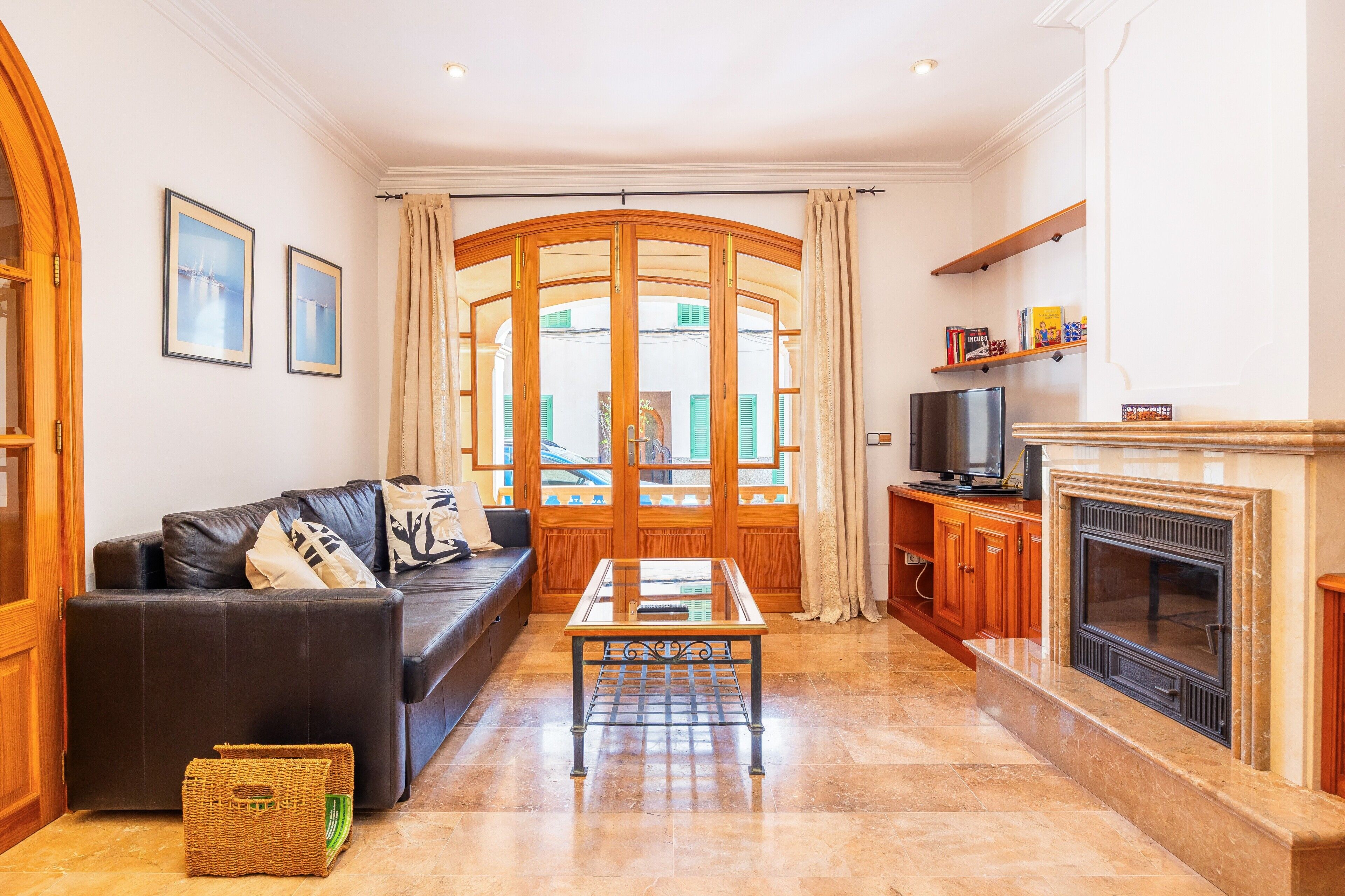 Una sala de estar con un sofá, una mesa de centro de vidrio, una chimenea y un televisor.