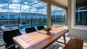 Une terrasse couverte avec une table en bois, des chaises et une plante en pot.
