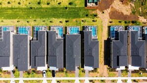 Oversigtsbillede af et boligkompleks med flere bygninger, hver med pool på taget.