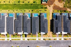 An aerial view of a residential complex with multiple buildings, each with a rooftop pool. - 6BR Family at Champions Gate, Pool & Game Room (Davenport)
