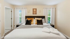 Una camera d'albergo con un letto, tende, una testiera, un quadro appeso al muro e un comodino.