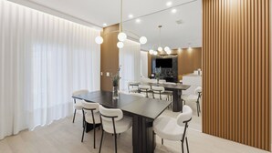 Un comedor moderno con una mesa larga, sillas blancas e iluminación colgante.