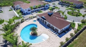 A residential area with a swimming pool, multiple houses, and a large building with a red roof. - Family 3BR Home in Lucaya Resort (Kissimmee)