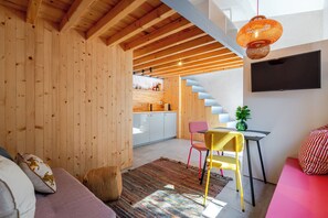 A modern interior with wooden walls, a staircase, a dining area with a table and chairs, and a TV mounted on the wall. - Kleine's House in Porto - Boavista (Porto)