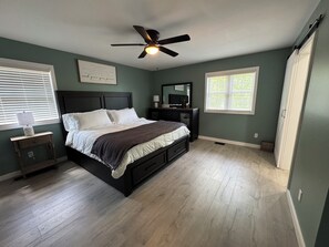 A bedroom with a bed, a ceiling fan, a dresser, a nightstand, and a window with blinds. - Newly renovated, one-level 3-bedroom home with a gorgeous Mountain View. (Otto)