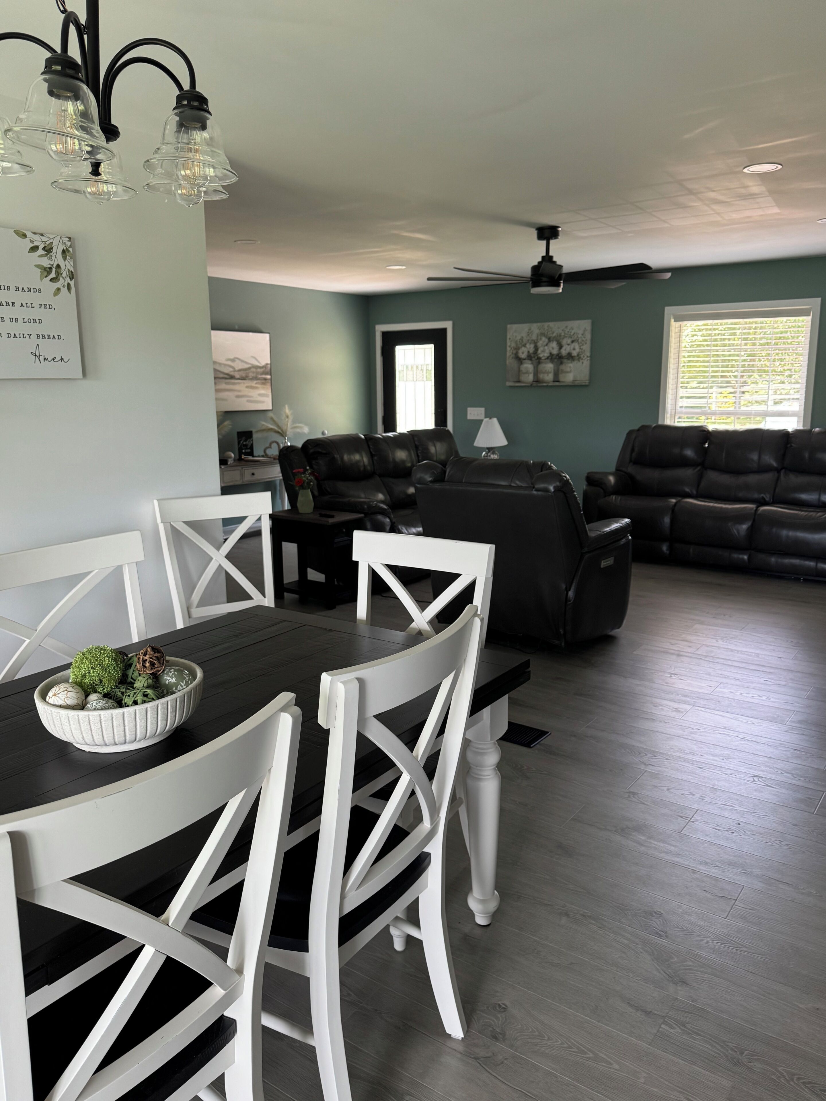 Un coin repas avec une table et des chaises, un salon avec un canapé et un ventilateur de plafond.