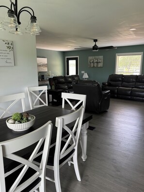 Un coin repas avec une table et des chaises, un salon avec un canapé et un ventilateur de plafond.