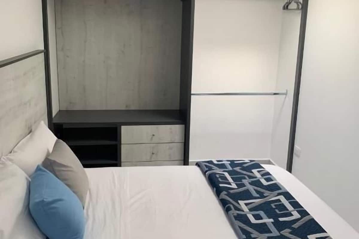 A bedroom with a bed, a wardrobe, and a built-in shower.