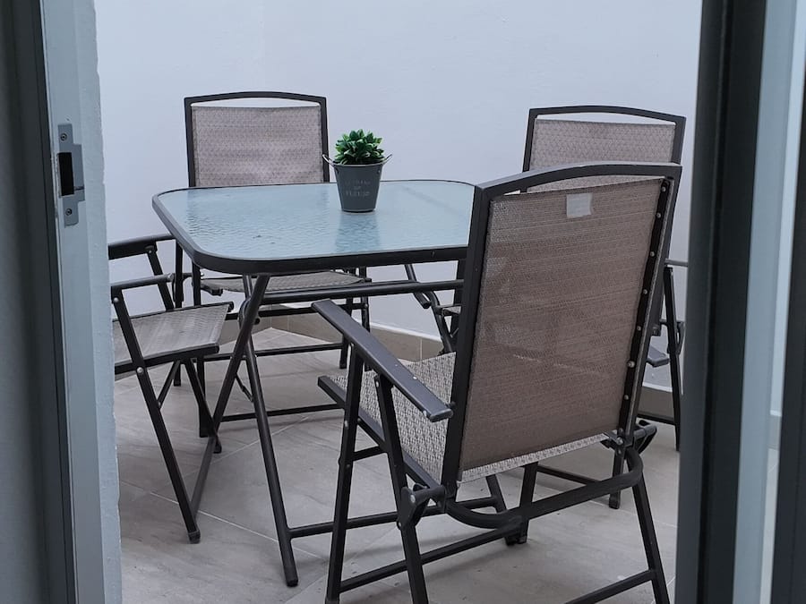 Eine Terrasse im Freien mit einem runden Tisch, vier Stühlen und einem Blumentopf.