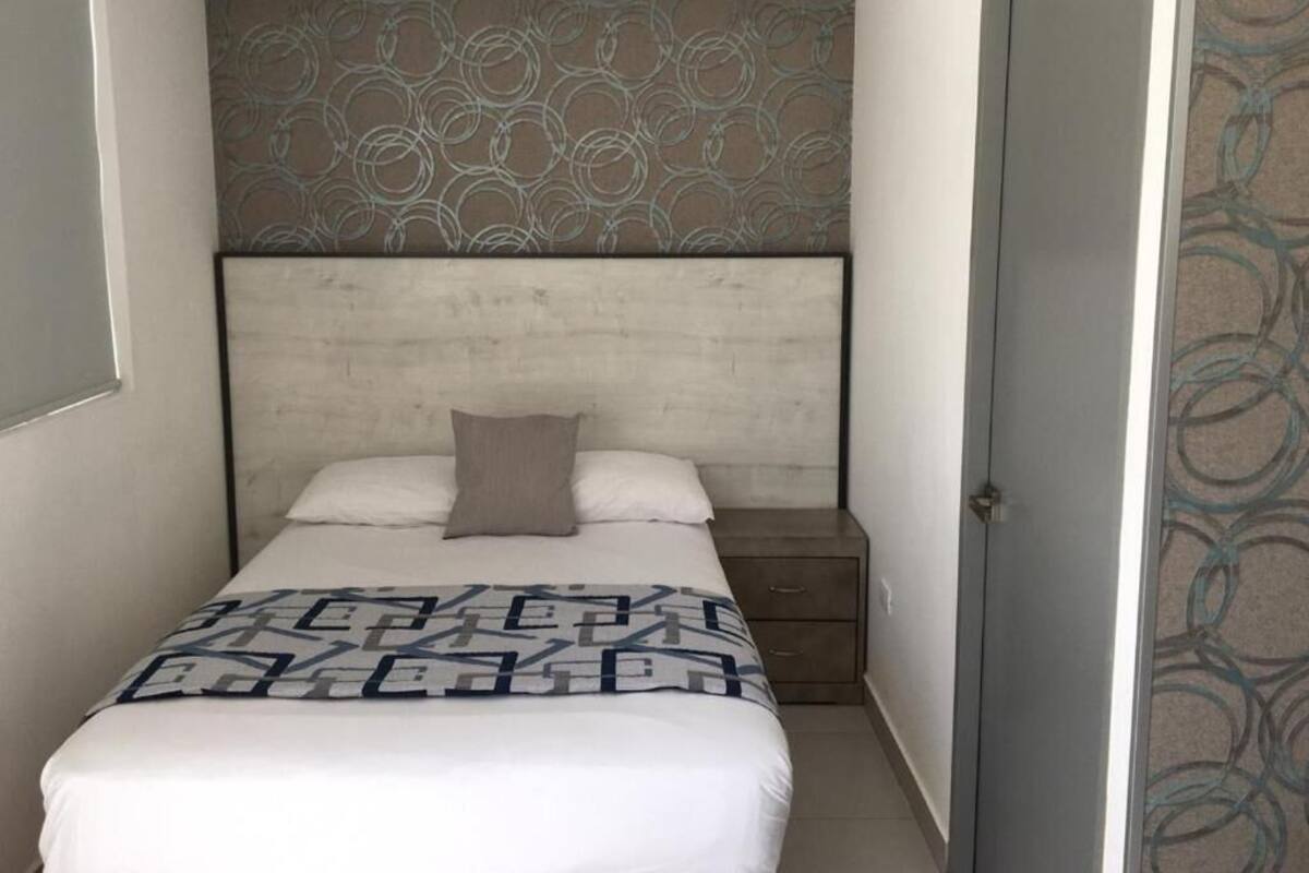 A small, neatly arranged bedroom with a bed, a nightstand, and a door.