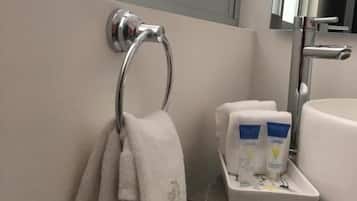 Un baño con un perchero, un lavabo y una bandeja con artículos de aseo.