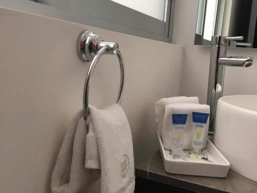Un baño con un perchero, un lavabo y una bandeja con artículos de aseo.