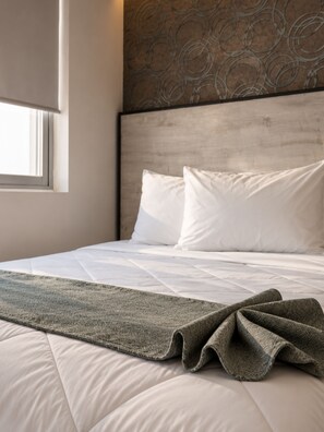 A neatly made bed with white bedding and a patterned throw blanket. - Suites Andre (Aguascalientes)