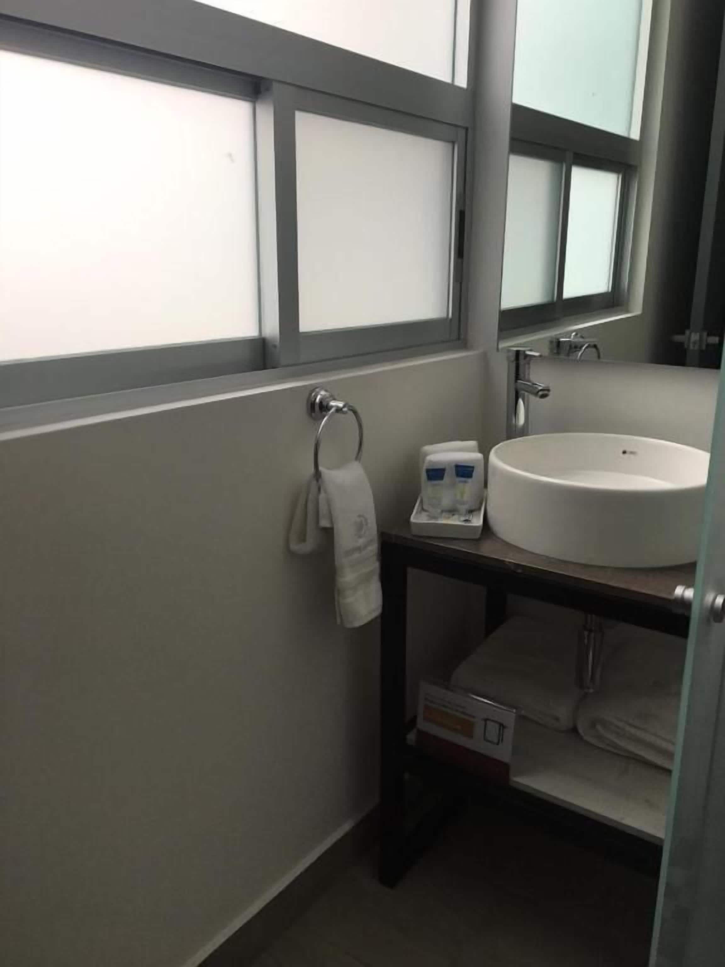 A bathroom with a white sink, a towel rack, and a mirror above the sink.