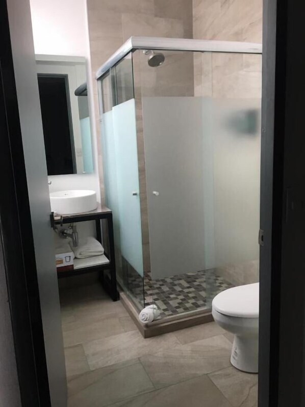 Uma casa de banho moderna com cabine de chuveiro em vidro, lavatório branco e sanita.