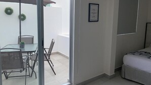 Ein modernes Zimmer mit einem Bett, einem Esstisch mit Stühlen, einem großen Fenster und einer Klimaanlage.