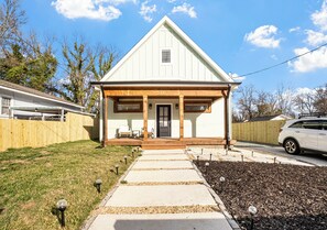 Une maison de plain-pied avec un porche à l’avant, une porte bien visible et une petite fenêtre.