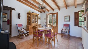 A dining area with wooden chairs, a table, a chandelier, and a wooden cabinet. - Villa 'Las Palmeras' with Mountain View, Wi-Fi and Air Conditioning (Illes Balears)