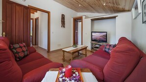 A living room with red sofas, a wooden ceiling, a TV, and a wooden table. - Villa 'Las Palmeras' with Mountain View, Wi-Fi and Air Conditioning (Illes Balears)