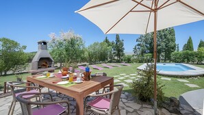 An outdoor patio with a wooden table, chairs, a barbecue grill, and a swimming pool. - Villa 'Las Palmeras' with Mountain View, Wi-Fi and Air Conditioning (Illes Balears)