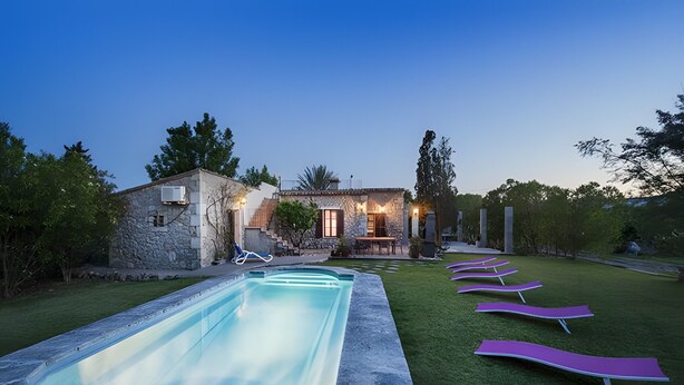 A pool with lounge chairs, a stone building, and a well-maintained lawn. - Villa 'Las Palmeras' with Mountain View, Wi-Fi and Air Conditioning (Illes Balears)