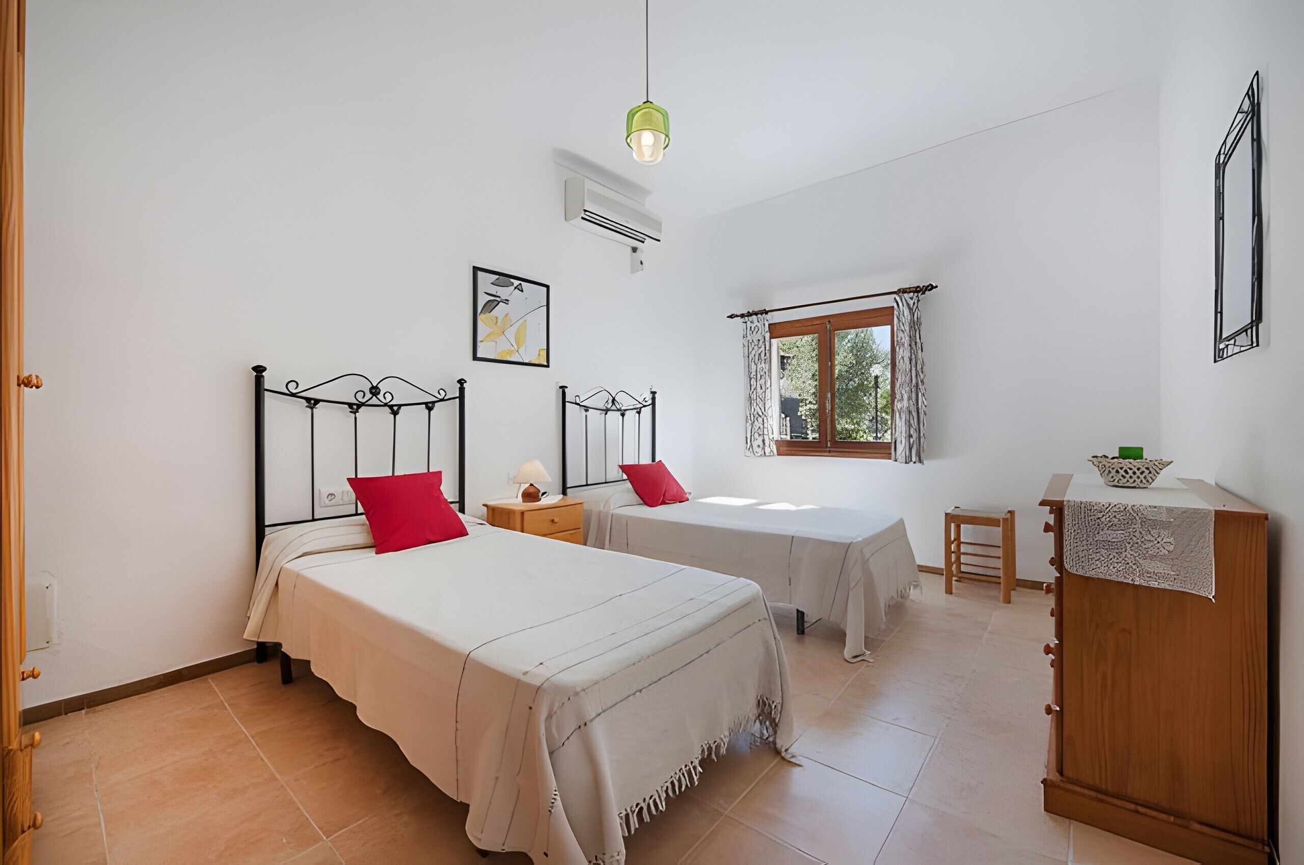 Une chambre avec deux lits, une petite table, une armoire et une fenêtre avec des rideaux.