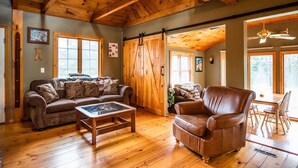 Ein gemütliches Wohnzimmer mit Holzboden, einem Ledersessel, einer Couch und einem Couchtisch.