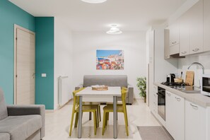 A compact kitchen with a dining table, chairs, and a sofa. - Azzurra Apartments Trinacria with Sea View, Wi-Fi, and Air Conditioning (Balestrate)