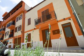 A multi-story building with balconies, a car parked in front, and a street view. - Azzurra Apartments Trinacria with Sea View, Wi-Fi, and Air Conditioning (Balestrate)