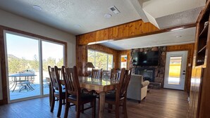 Un'ampia sala da pranzo con un grande tavolo in legno e sedie, un camino in pietra e una televisione a parete.