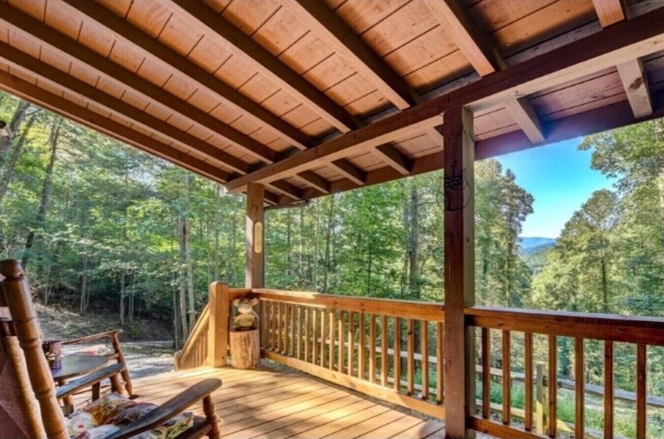 A wooden deck with a railing overlooking a forested area.
